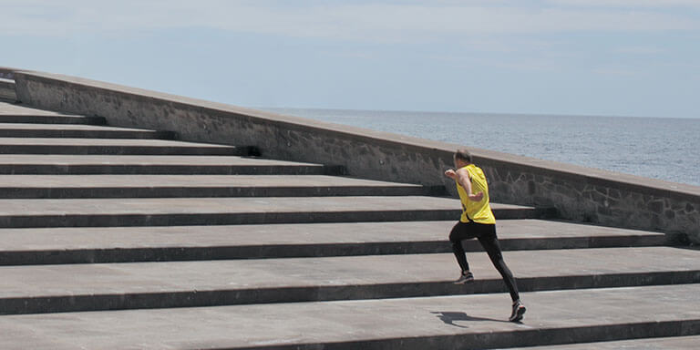 A man in yellow athletic clothes running up a set of concrete steps